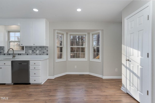 kitchen with sink, white cabinetry, dark hardwood / wood-style flooring, dishwasher, and decorative backsplash