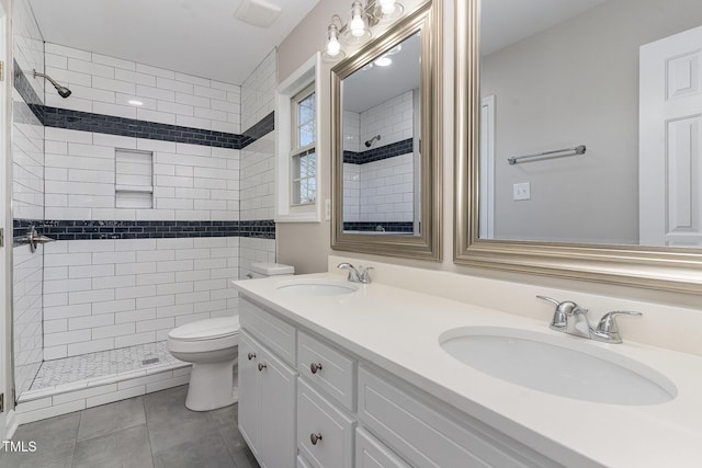 bathroom with tiled shower, vanity, toilet, and tile patterned flooring