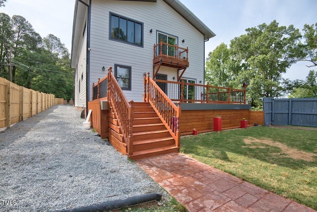 rear view of house featuring a lawn and a deck