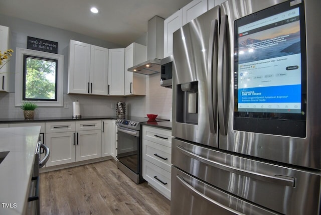 kitchen with white cabinetry, appliances with stainless steel finishes, light hardwood / wood-style flooring, and decorative backsplash