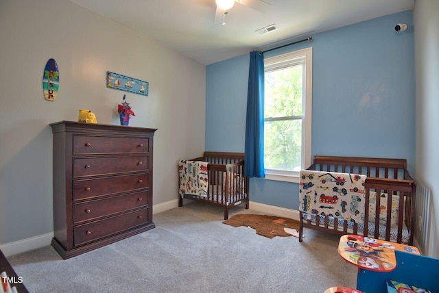 carpeted bedroom featuring multiple windows, a nursery area, and ceiling fan