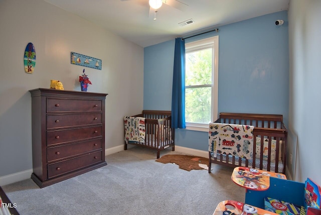 bedroom featuring a crib, light carpet, and ceiling fan