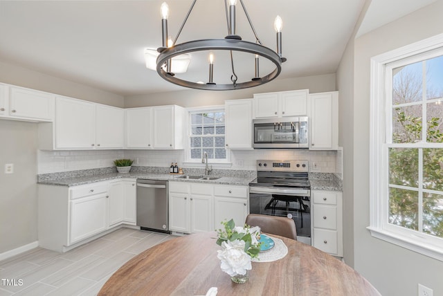 kitchen featuring white cabinetry, sink, light stone countertops, and appliances with stainless steel finishes