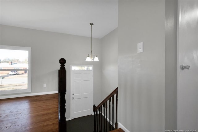 foyer entrance with dark wood-style floors, a notable chandelier, and baseboards