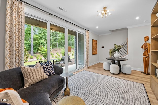 living room with a notable chandelier, ornamental molding, and light wood-type flooring