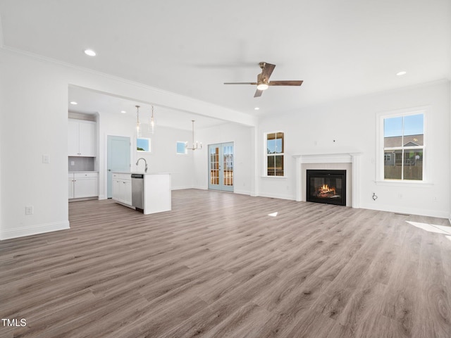 unfurnished living room featuring a glass covered fireplace, light wood-style flooring, and baseboards