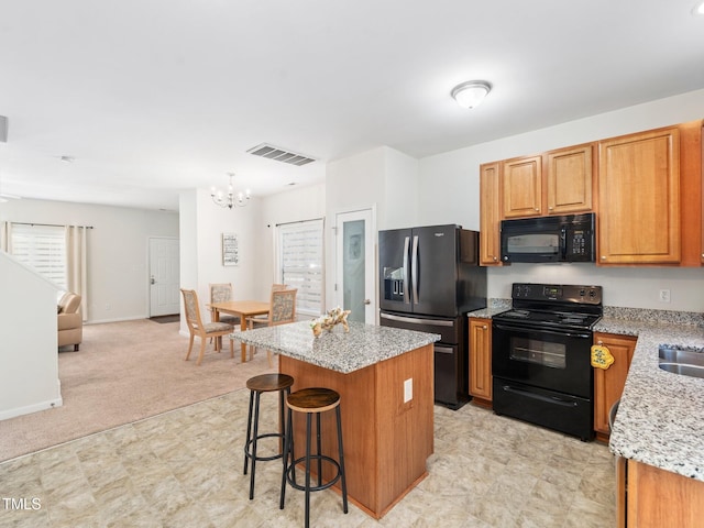 kitchen with an inviting chandelier, visible vents, black appliances, a kitchen island, and open floor plan