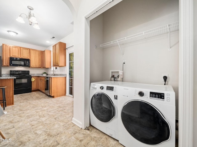 clothes washing area featuring a notable chandelier, washing machine and clothes dryer, visible vents, laundry area, and a sink