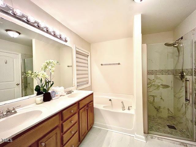 full bathroom with a garden tub, a sink, and a stall shower