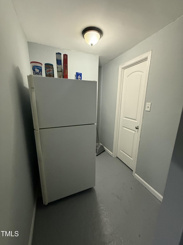 interior space with white refrigerator and concrete flooring