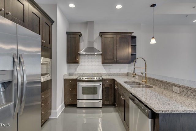 kitchen with sink, hanging light fixtures, light stone counters, stainless steel appliances, and wall chimney exhaust hood