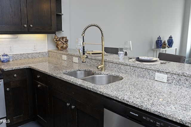 kitchen featuring dark brown cabinets, light stone counters, a sink, dishwasher, and backsplash