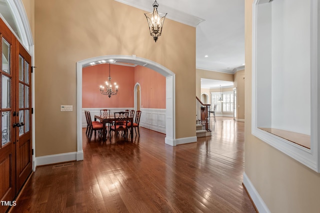 entryway featuring ornamental molding, dark wood-type flooring, and an inviting chandelier