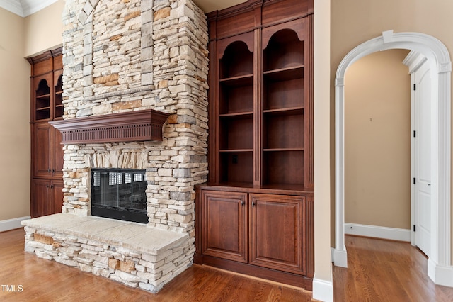 unfurnished living room with ornamental molding, wood-type flooring, and a fireplace