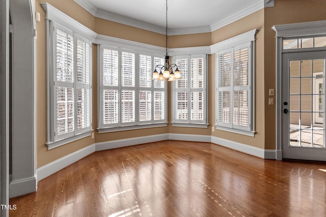 unfurnished dining area featuring an inviting chandelier, hardwood / wood-style floors, and crown molding