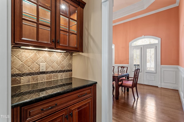 bar featuring crown molding, tasteful backsplash, and light hardwood / wood-style flooring