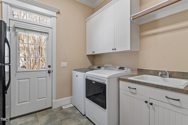 washroom featuring cabinets, ornamental molding, sink, and washing machine and clothes dryer