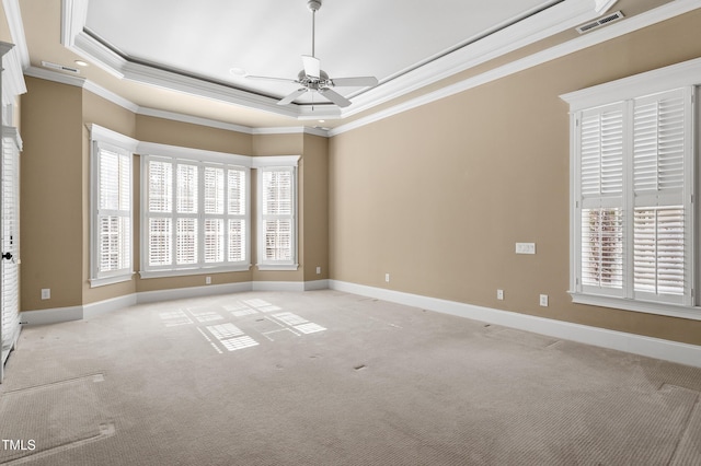 unfurnished room with a tray ceiling, ornamental molding, light colored carpet, and a healthy amount of sunlight