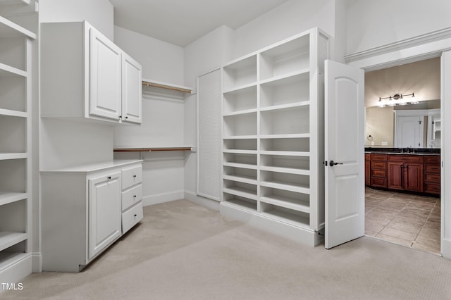 walk in closet featuring sink and light colored carpet