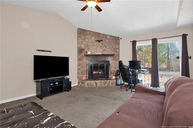 living room featuring ceiling fan, a stone fireplace, vaulted ceiling, and carpet