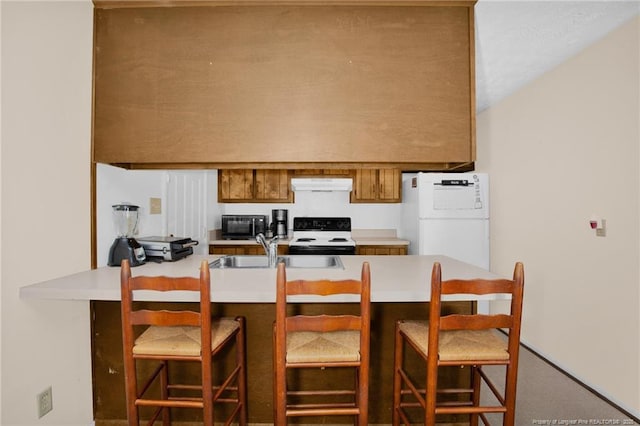 kitchen featuring sink, a breakfast bar area, kitchen peninsula, white fridge, and electric stove