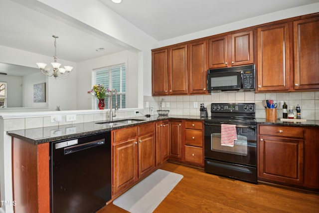 kitchen featuring decorative light fixtures, tasteful backsplash, sink, dark stone counters, and black appliances