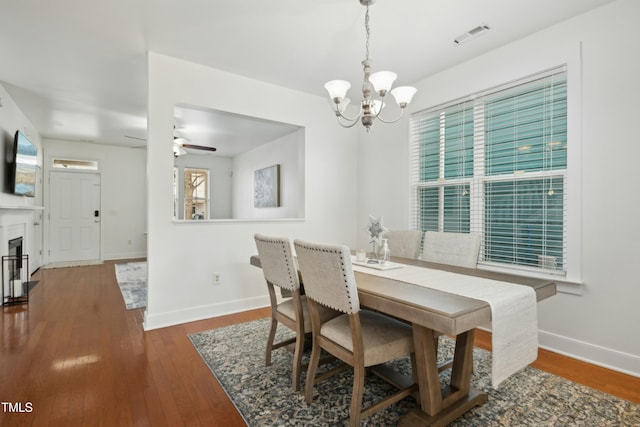 dining room featuring ceiling fan with notable chandelier and dark hardwood / wood-style flooring