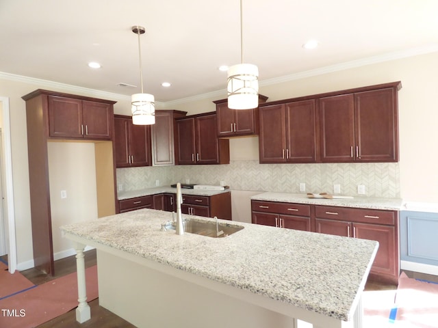 kitchen featuring pendant lighting, sink, light stone countertops, and an island with sink