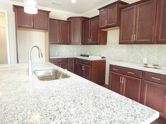 kitchen featuring sink, hanging light fixtures, light stone counters, tasteful backsplash, and ornamental molding