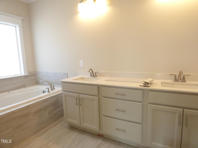 bathroom with tiled tub and vanity