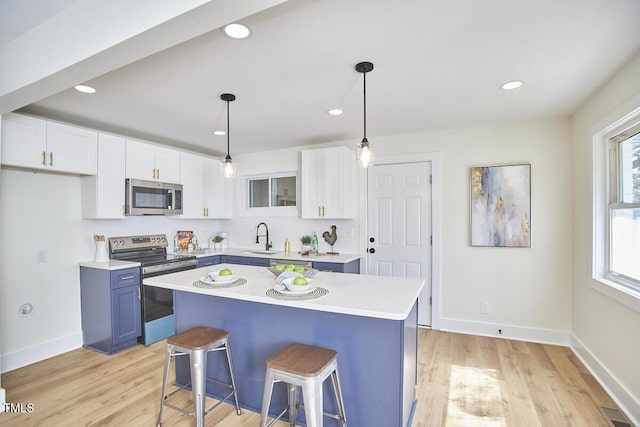 kitchen featuring white cabinetry, stainless steel appliances, blue cabinetry, and hanging light fixtures