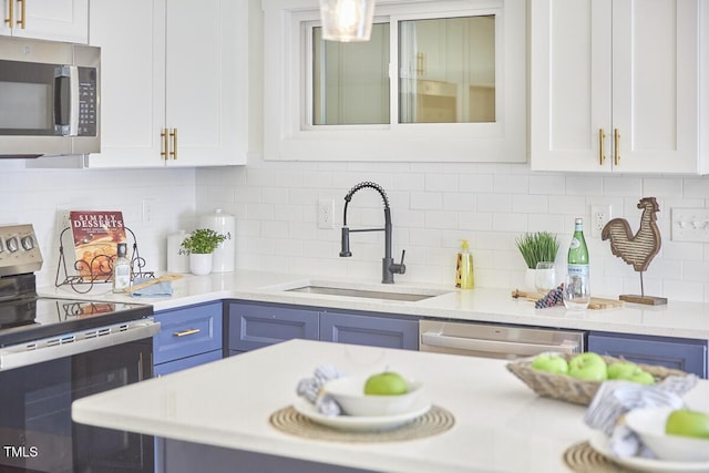 kitchen featuring blue cabinets, white cabinetry, sink, backsplash, and stainless steel appliances