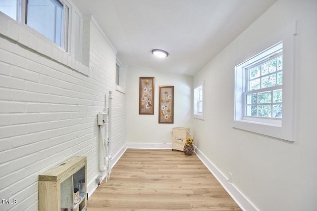 laundry room with light hardwood / wood-style flooring and brick wall