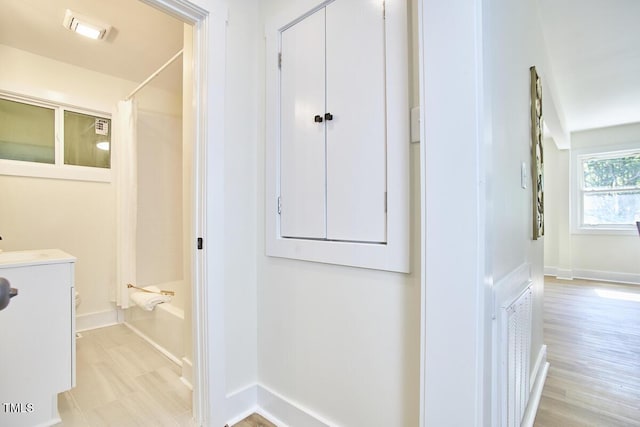 interior space with vanity, wood-type flooring, and shower / bathtub combination with curtain