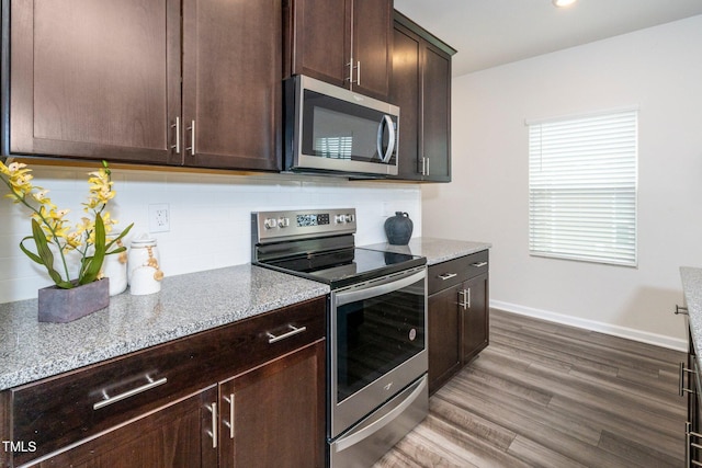 kitchen featuring light stone counters, backsplash, dark brown cabinets, and stainless steel appliances