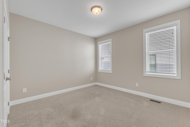 unfurnished room featuring light colored carpet, visible vents, and baseboards