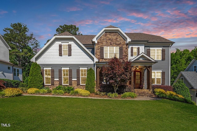 craftsman-style home with stone siding and a yard