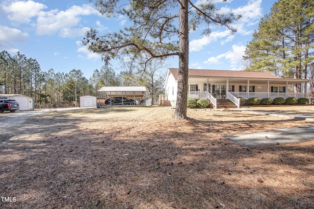 ranch-style house with a porch, a carport, and a storage unit