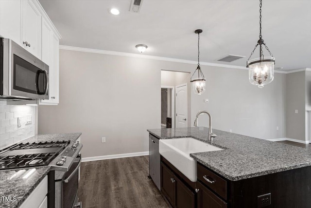 kitchen featuring hanging light fixtures, an island with sink, appliances with stainless steel finishes, and white cabinets