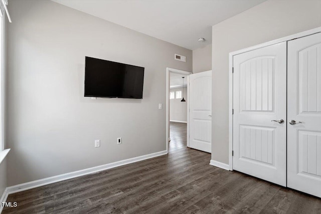 unfurnished bedroom featuring dark hardwood / wood-style flooring and a closet