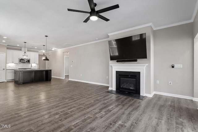 unfurnished living room with dark wood-type flooring, ceiling fan, and crown molding