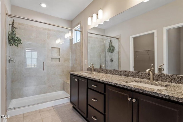 bathroom with a shower with door, vanity, and tile patterned floors