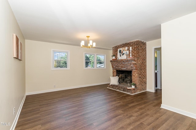 unfurnished living room featuring an inviting chandelier, a fireplace, and dark hardwood / wood-style floors