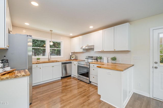 kitchen with stainless steel appliances, butcher block counters, and white cabinets