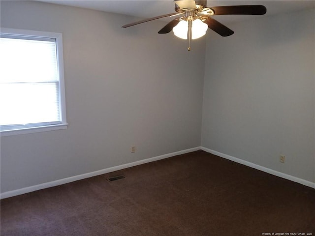 spare room with ceiling fan and dark carpet