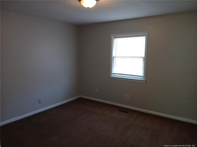 spare room featuring dark carpet