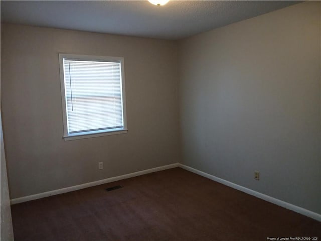 spare room with dark carpet