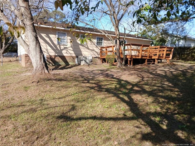 back of property with a wooden deck and a yard