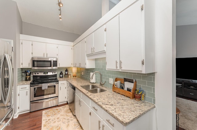 kitchen with sink, decorative backsplash, white cabinets, and appliances with stainless steel finishes