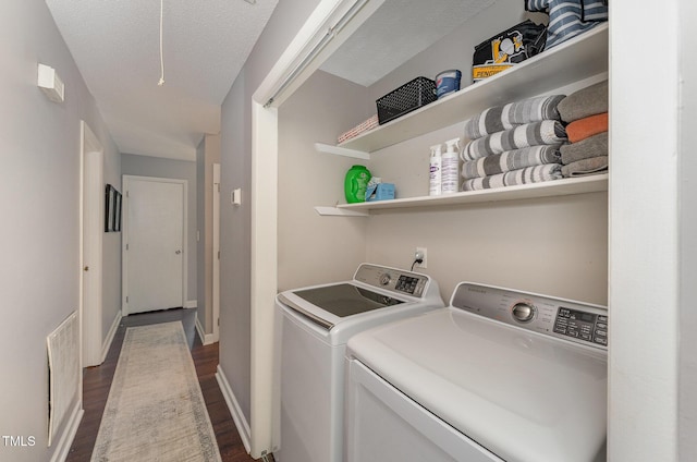 clothes washing area featuring dark hardwood / wood-style floors, washer and dryer, and a textured ceiling